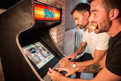 Dos clientes jugando a la máquina recreativa de Porco Dio