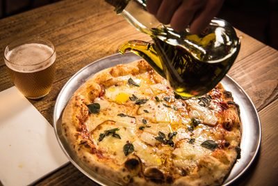 Pizza napolitana de Porco Dio con una cerveza